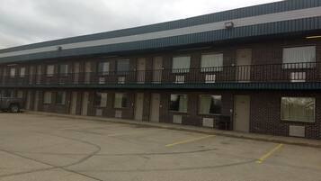 Un motel de varios pisos con fachada de ladrillo, habitaciones numeradas y estacionamiento.