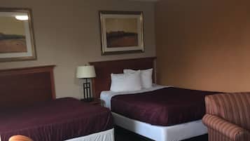 A hotel room with two beds, a nightstand, a lamp, and striped furniture.