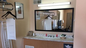 Une salle de bain d’hôtel équipée d’un lavabo, d’un miroir, d’un porte-serviettes et d’un panneau indiquant le service de blanchisserie.
