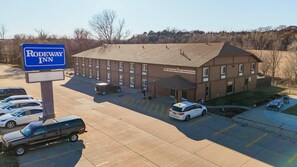A motel with a signboard, parking area, and a building with multiple windows.