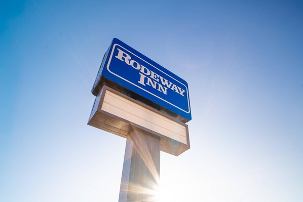 A sign for Rodeway Inn against a clear sky.