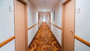Ein Hotelkorridor mit Teppichböden, Holllaufstangen und Türen mit den Nummern 101 und 102.