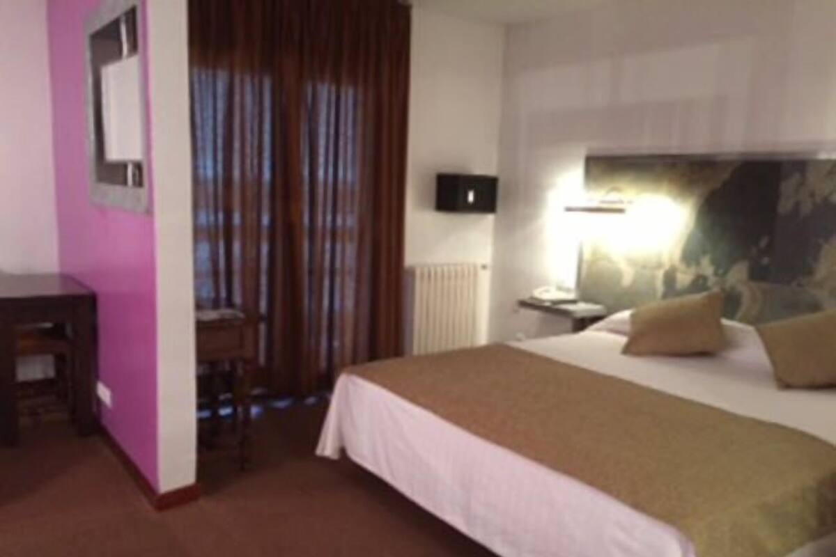A hotel room with a bed, a desk, and a chair.