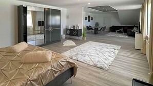 A modern bedroom with a bed, a large mirror, and a seating area with a table and chairs.