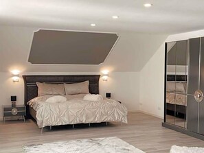 A bedroom with a large bed, bedside lamps, a wardrobe, and a ceiling light fixture.
