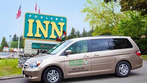 A van parked in front of a hotel sign with the name 'Poulson Inn & Suites'.