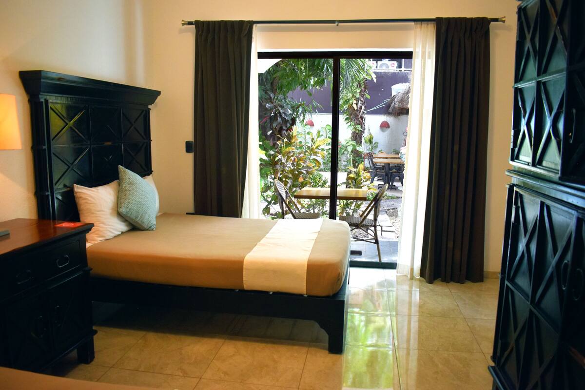Une chambre d’hôtel avec un lit, une table de chevet et une vue sur l’espace extérieur grâce à une porte-fenêtre coulissante.