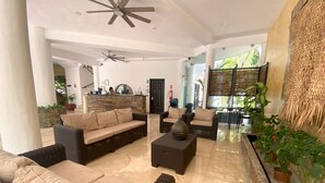 A spacious lobby with wicker furniture, a reception desk, and potted plants. - Hotel Hacienda Paradise (Playa del Carmen)