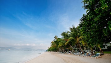 Na praia, espreguiçadeiras, guarda-sóis, toalhas de praia