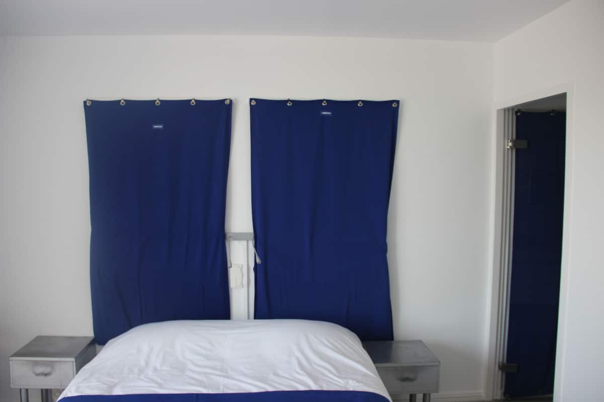 Un dormitorio con una cama, dos mesitas de noche y una puerta.