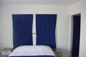 Un dormitorio con una cama, dos mesitas de noche y una puerta.
