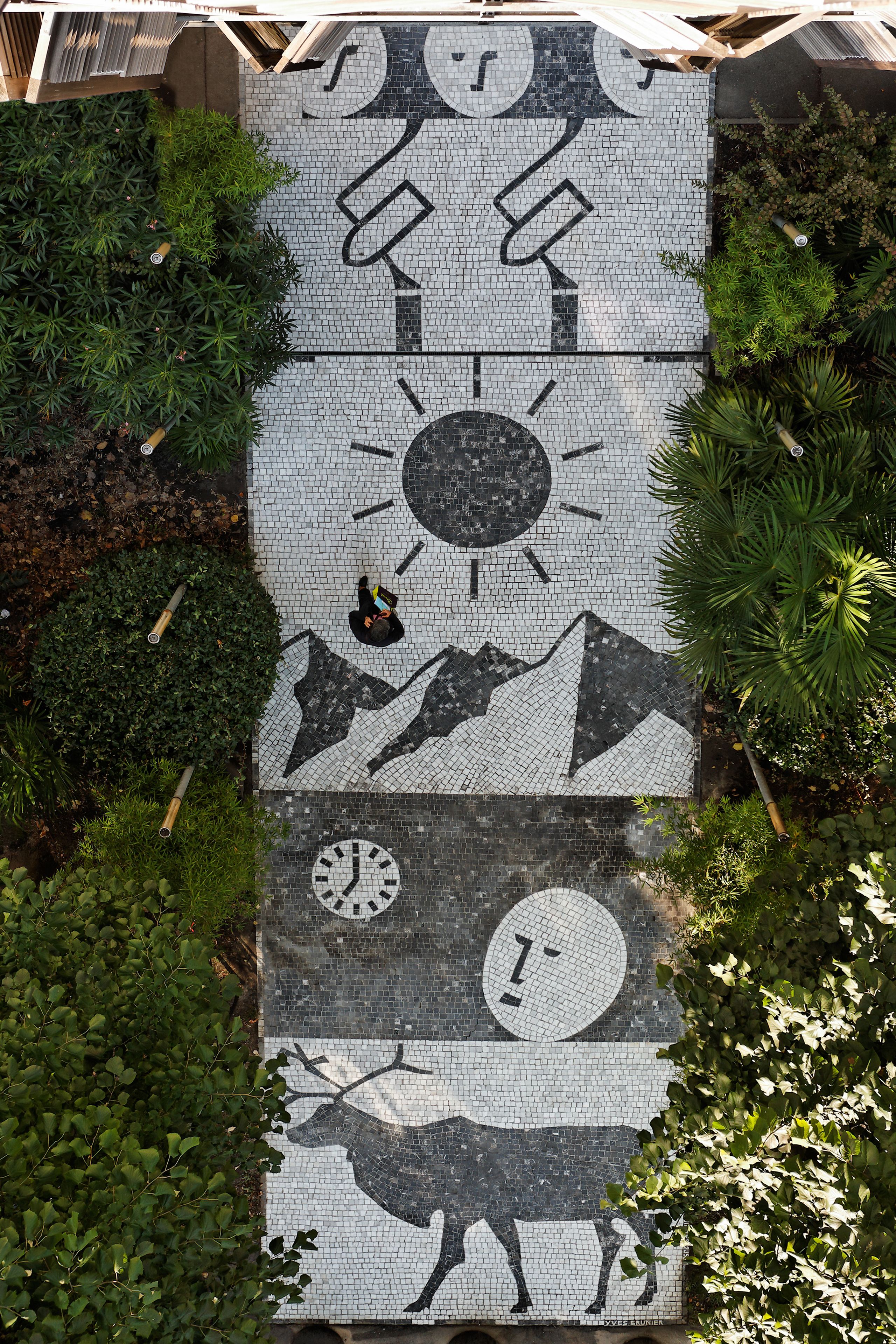 Un muro de mosaico con diseños geométricos y la silueta de un ciervo.