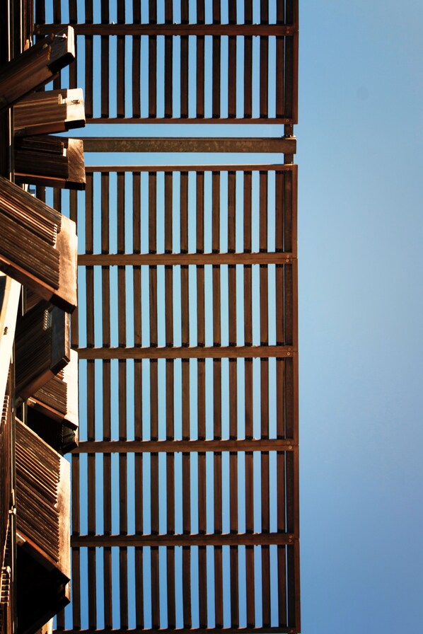 Primer plano de una estructura de madera con listones verticales sobre un cielo despejado.