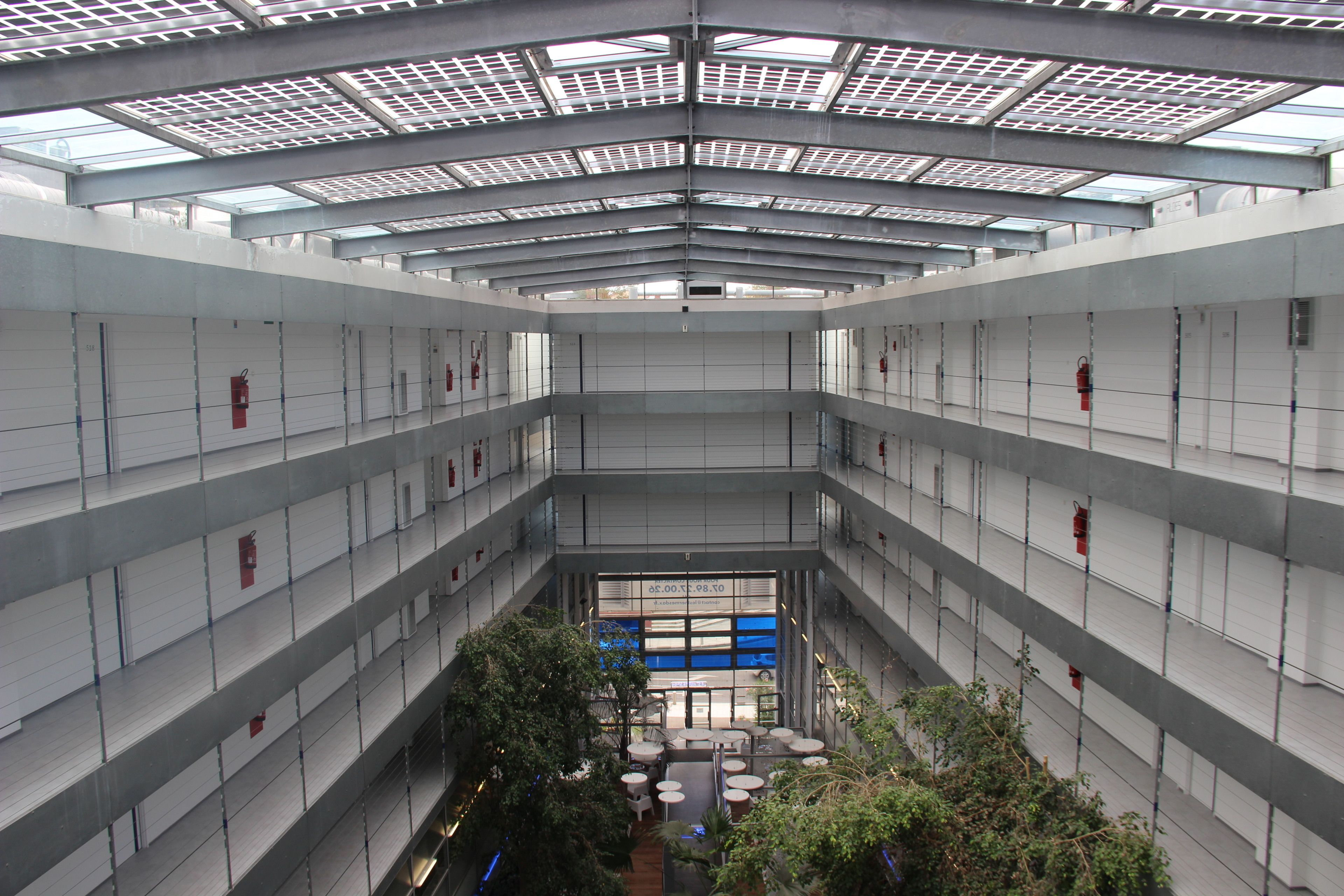 A multi-level atrium with skylights, a central seating area, and fire extinguishers on the walls.