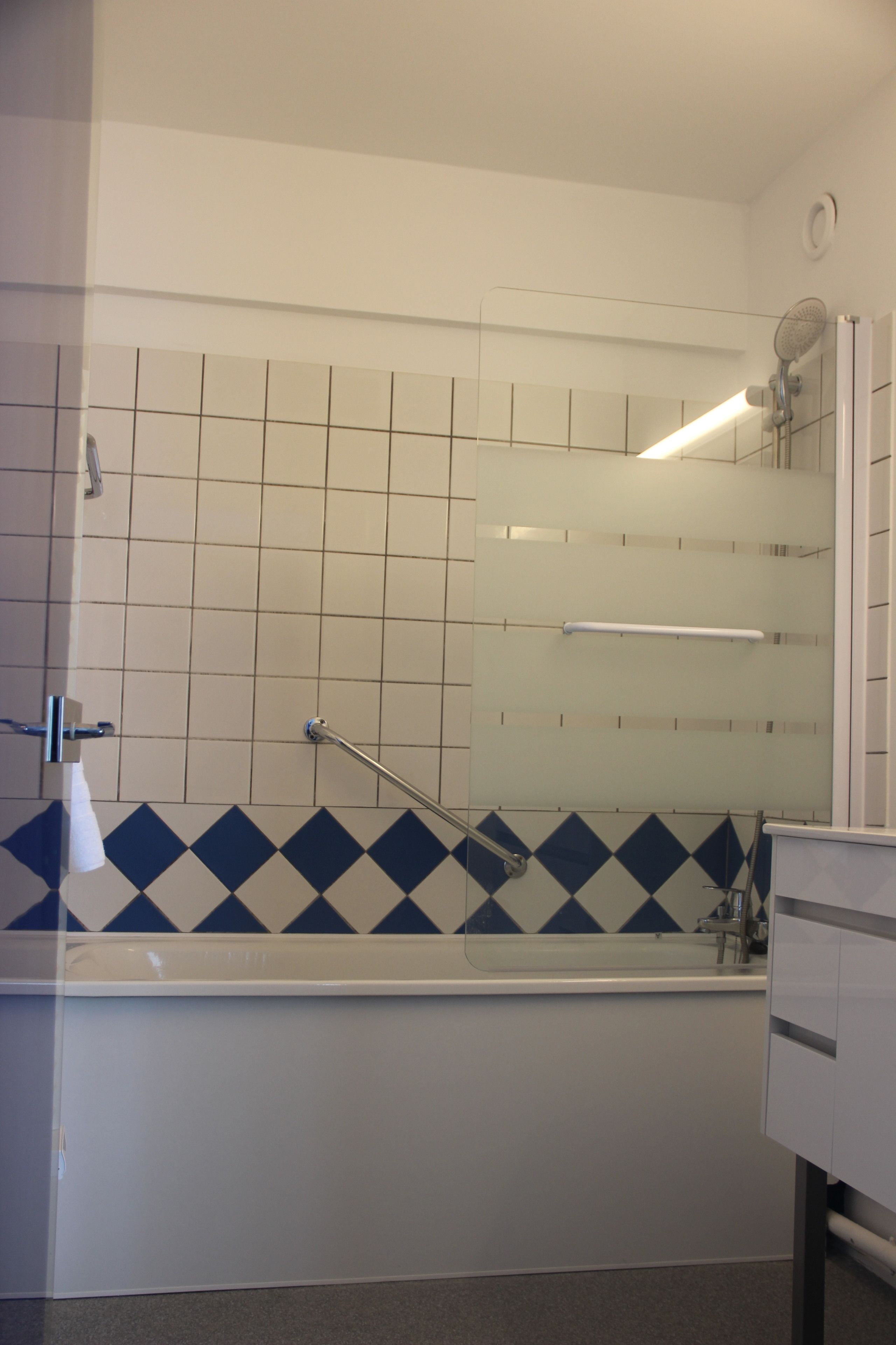 A bathroom with a bathtub, a shower, and a mirror.