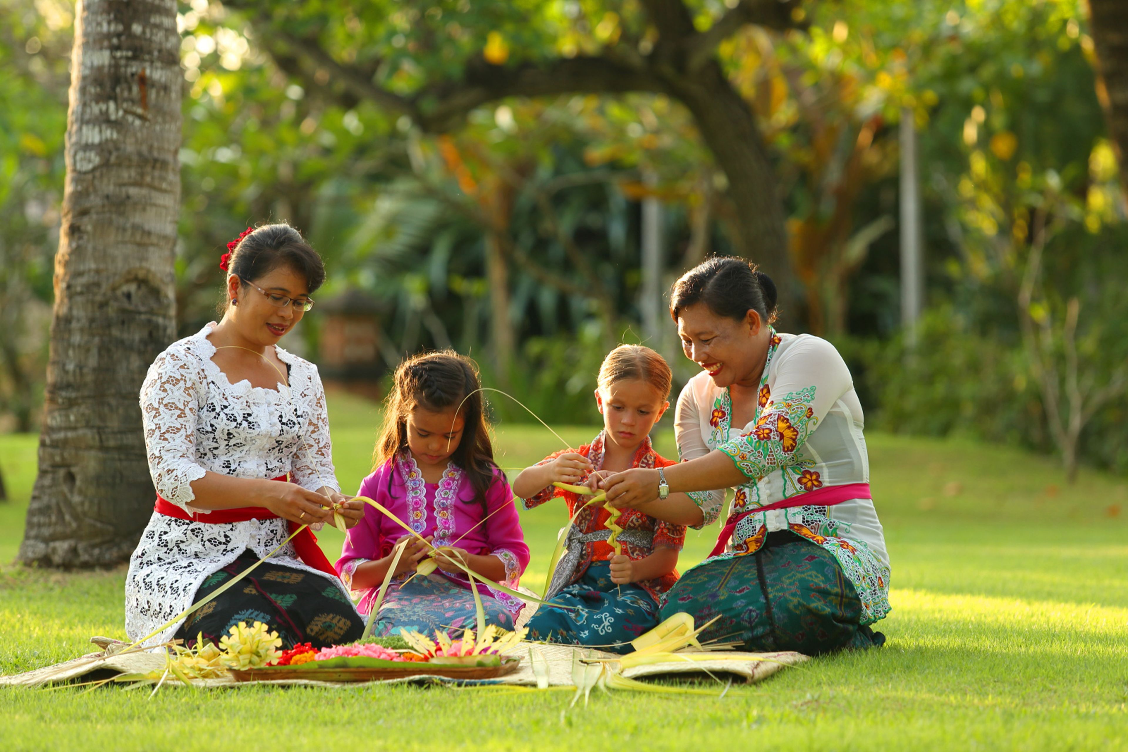 Four individuals engaged in an outdoor activity on a grassy field with trees in the background.