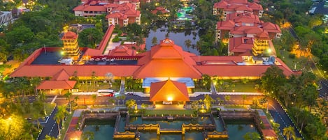 A resort with multiple buildings, a central pool, and a view of the ocean.
