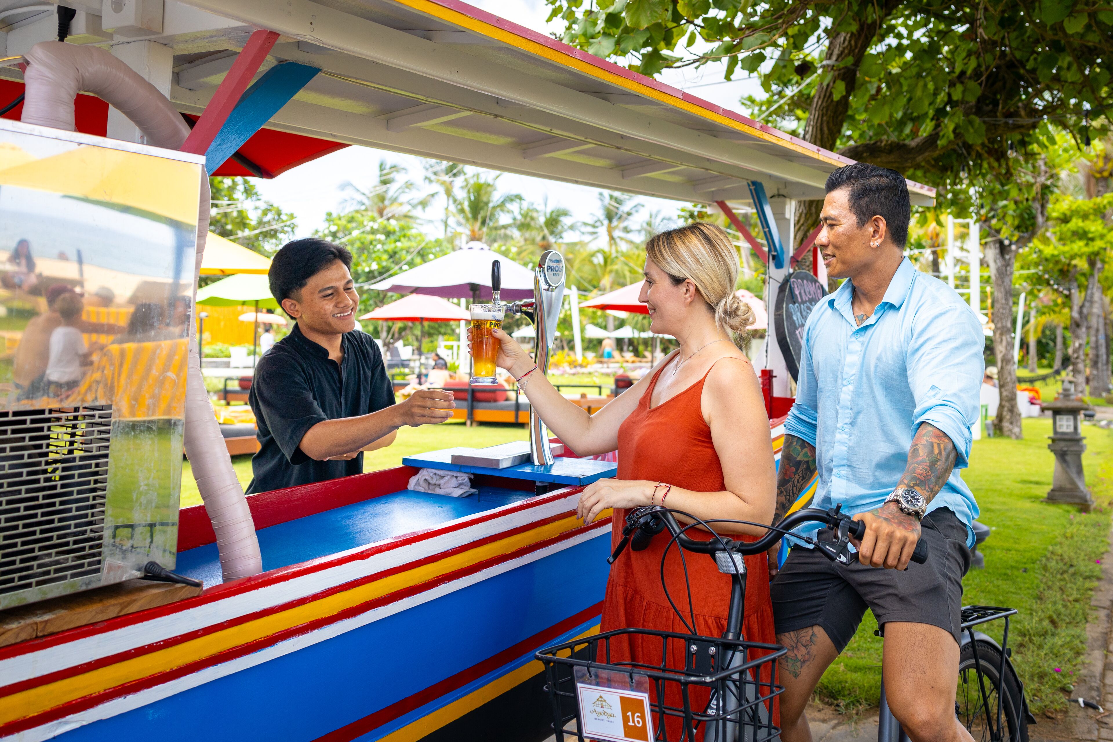 A colorful food truck with a beer tap, a customer ordering, and a person on a bicycle nearby.