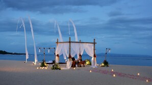 A beach wedding setup with a canopy, floral decorations, and candles.