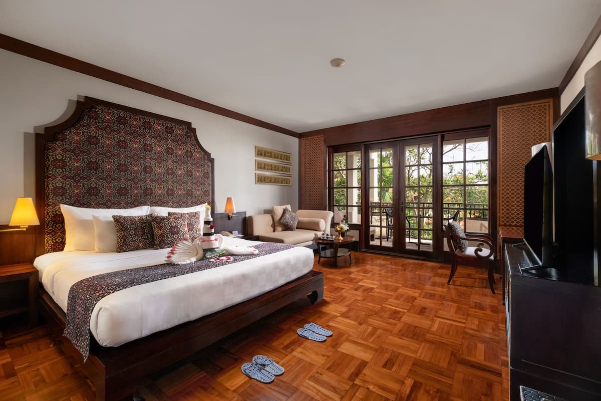 Une chambre spacieuse avec un grand lit, un canapé, une télévision et un balcon offrant une vue agréable.