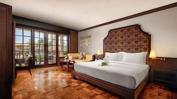 Een hotelkamer met een groot bed, een slaapbank, een fauteuil, een nachtkastje en een open haard.