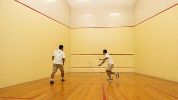 A squash court with wooden flooring and yellow walls.