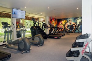 Un gimnasio con cintas de correr, elípticas y una banca de pesas.