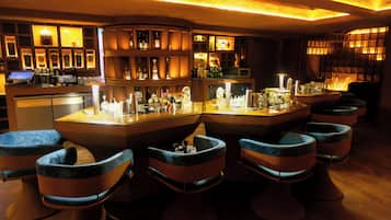 A bar area with a curved counter, multiple stools, and shelves stocked with bottles.