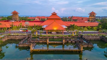A traditional building with a central pavilion and two smaller structures, surrounded by a water feature and greenery.