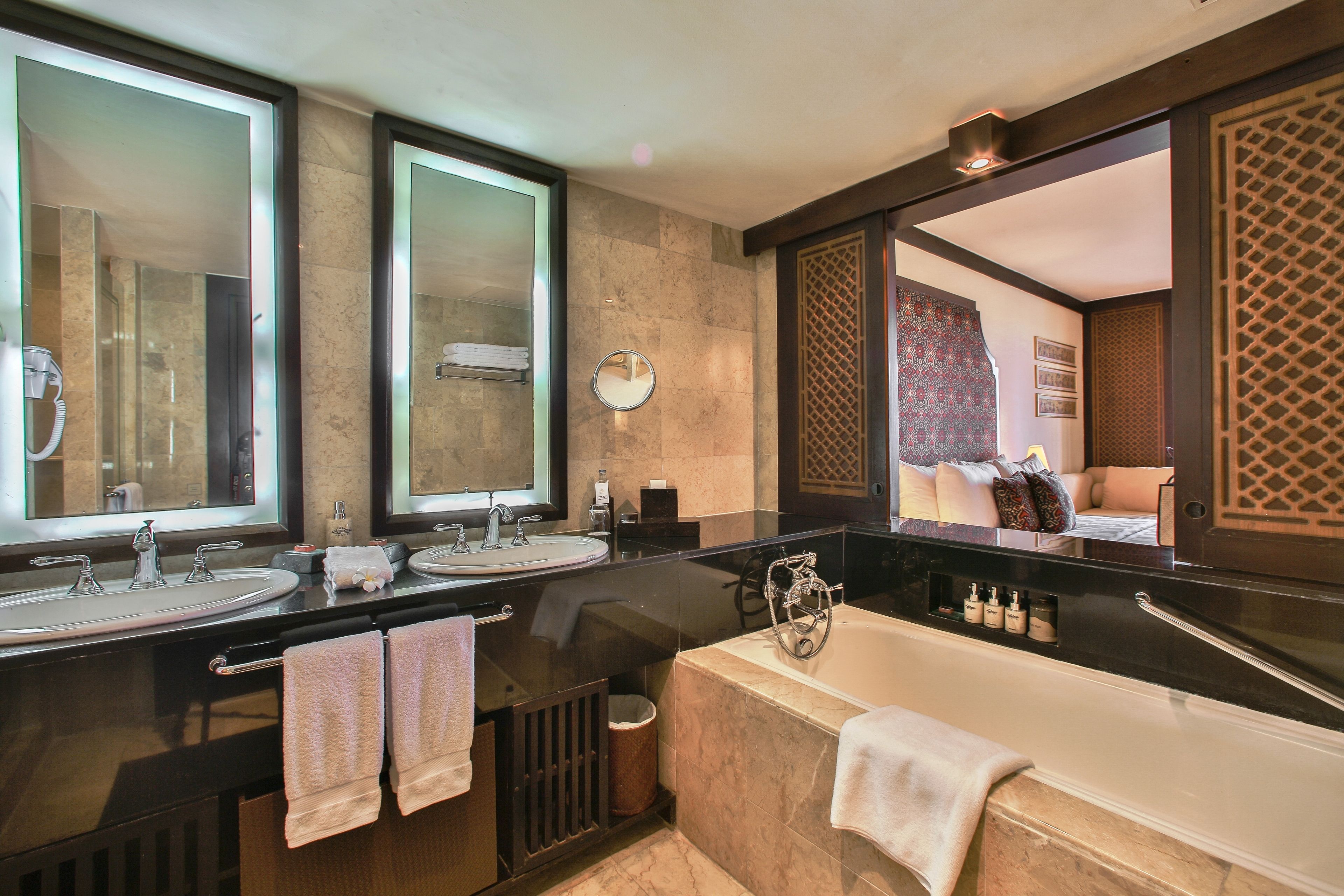 A modern bathroom with two sinks, a bathtub, and large mirrors.