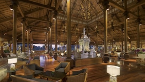 A spacious lobby with high ceilings, wooden beams, and a central decorative fountain.