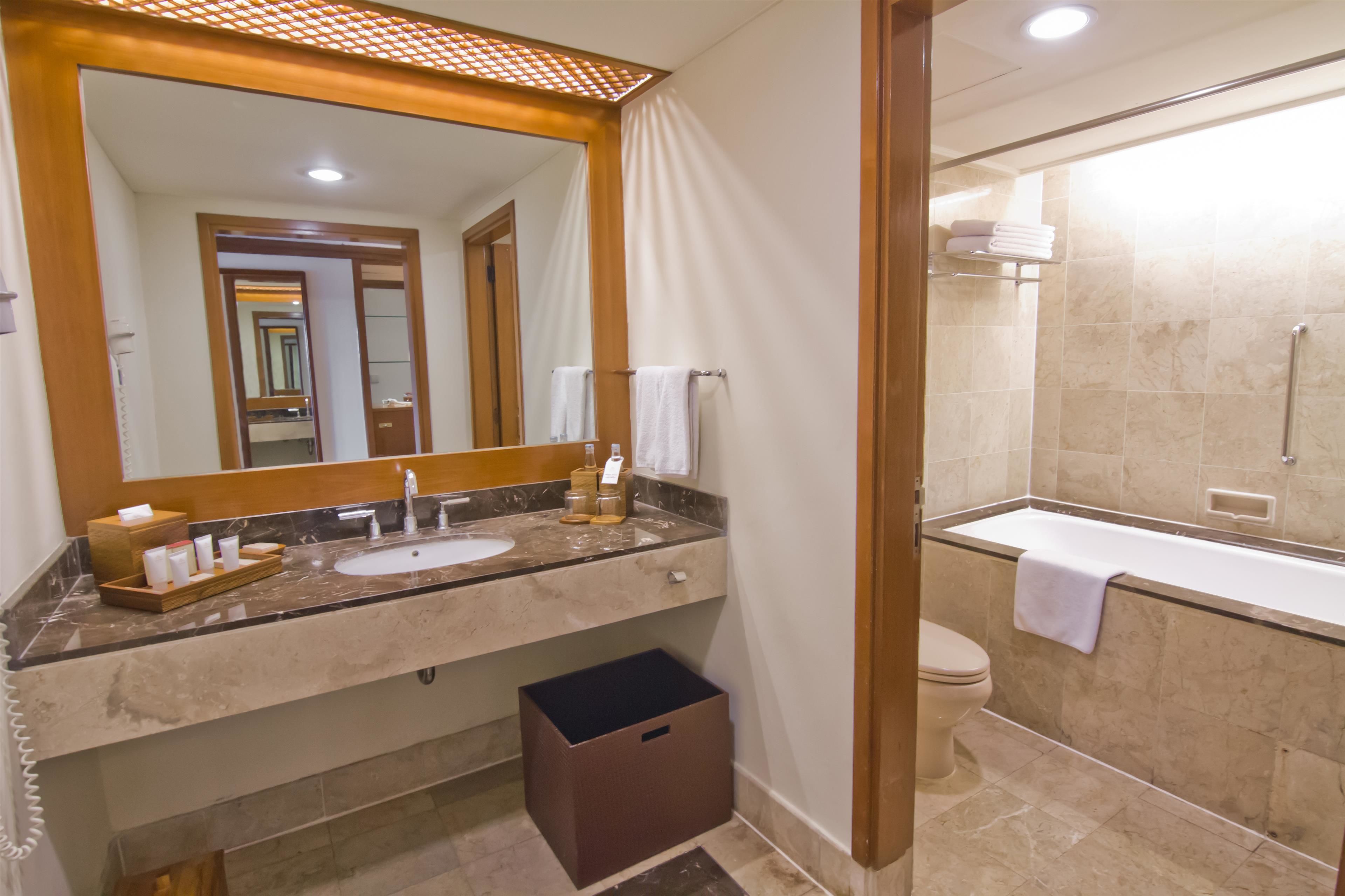 A modern bathroom with a large mirror, a sink, and a bathtub.