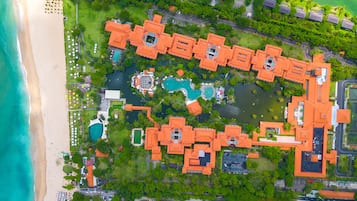 An aerial view of a resort with multiple buildings, a beach, and a central pool area.