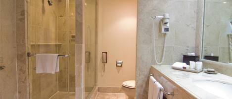 A modern bathroom with a glass-enclosed shower, a toilet, and a vanity with a mirror.
