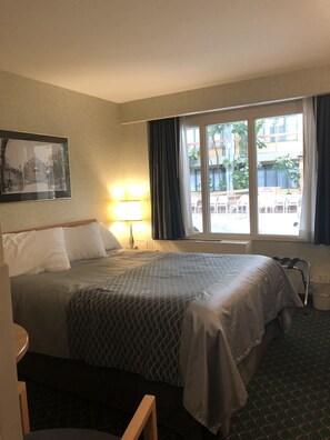 Relax in this inviting room with a comfortable bed, bedside table, and window offering a view of the surrounding area.