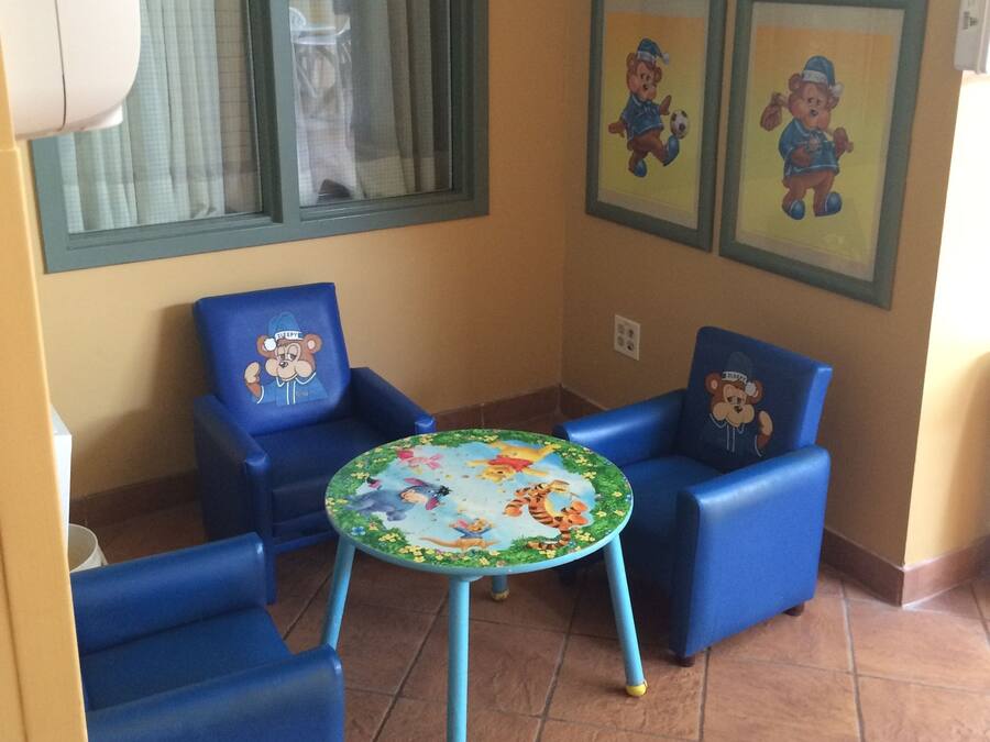 A small room with blue chairs, a round table with a colorful design, and framed pictures on the wall.