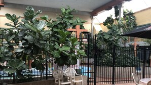 Un patio al aire libre con suelo de baldosas, dos sillas de plástico y una mesa.
