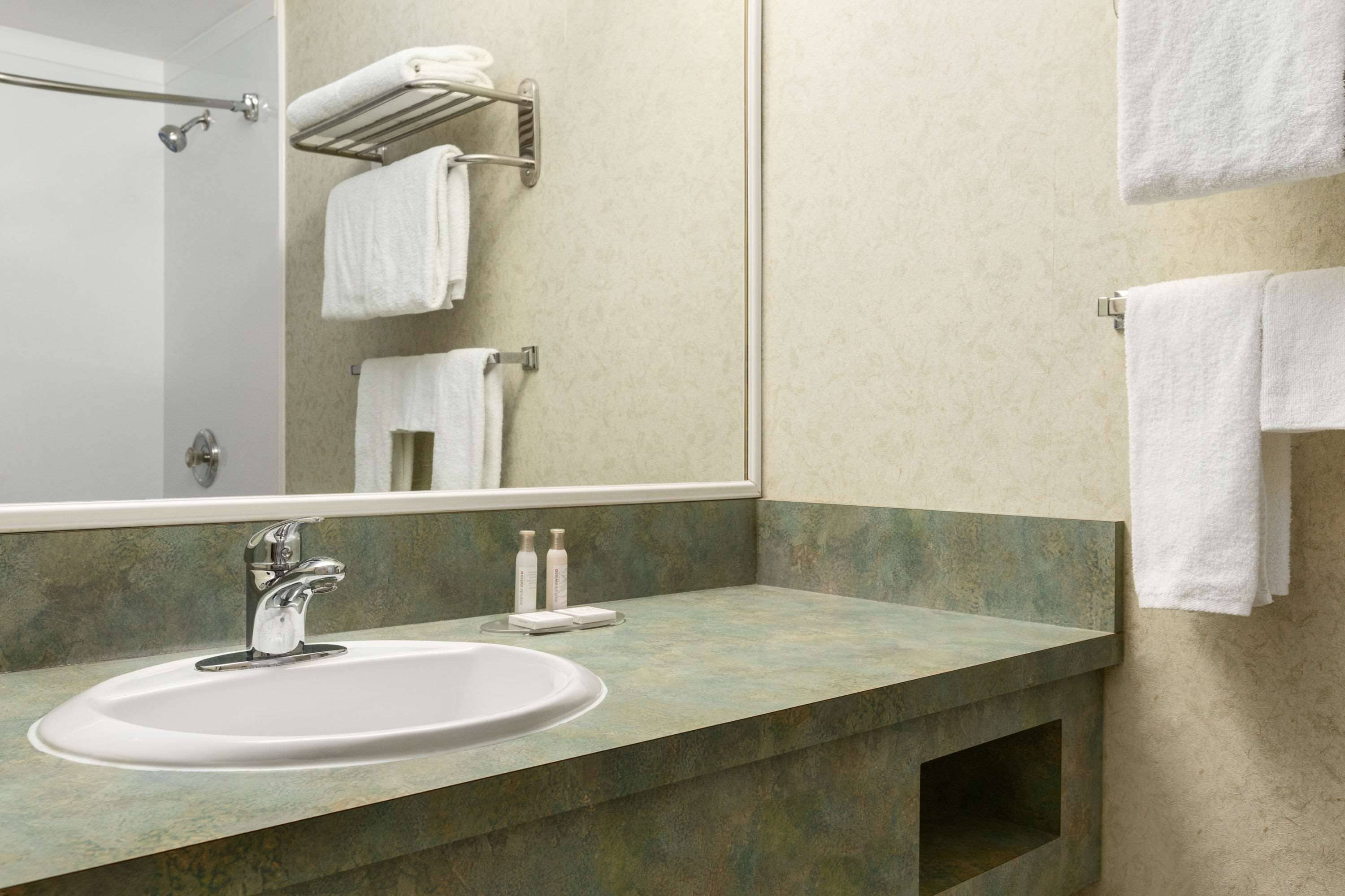 A bathroom with a sink, mirror, and towel rack.