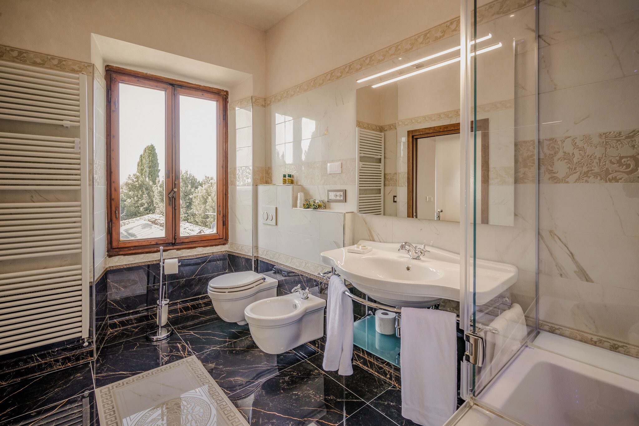 Ein modernes Badezimmer mit großem Fenster, einem Bidet, einer Badewanne und einem Waschtisch mit Spiegel.