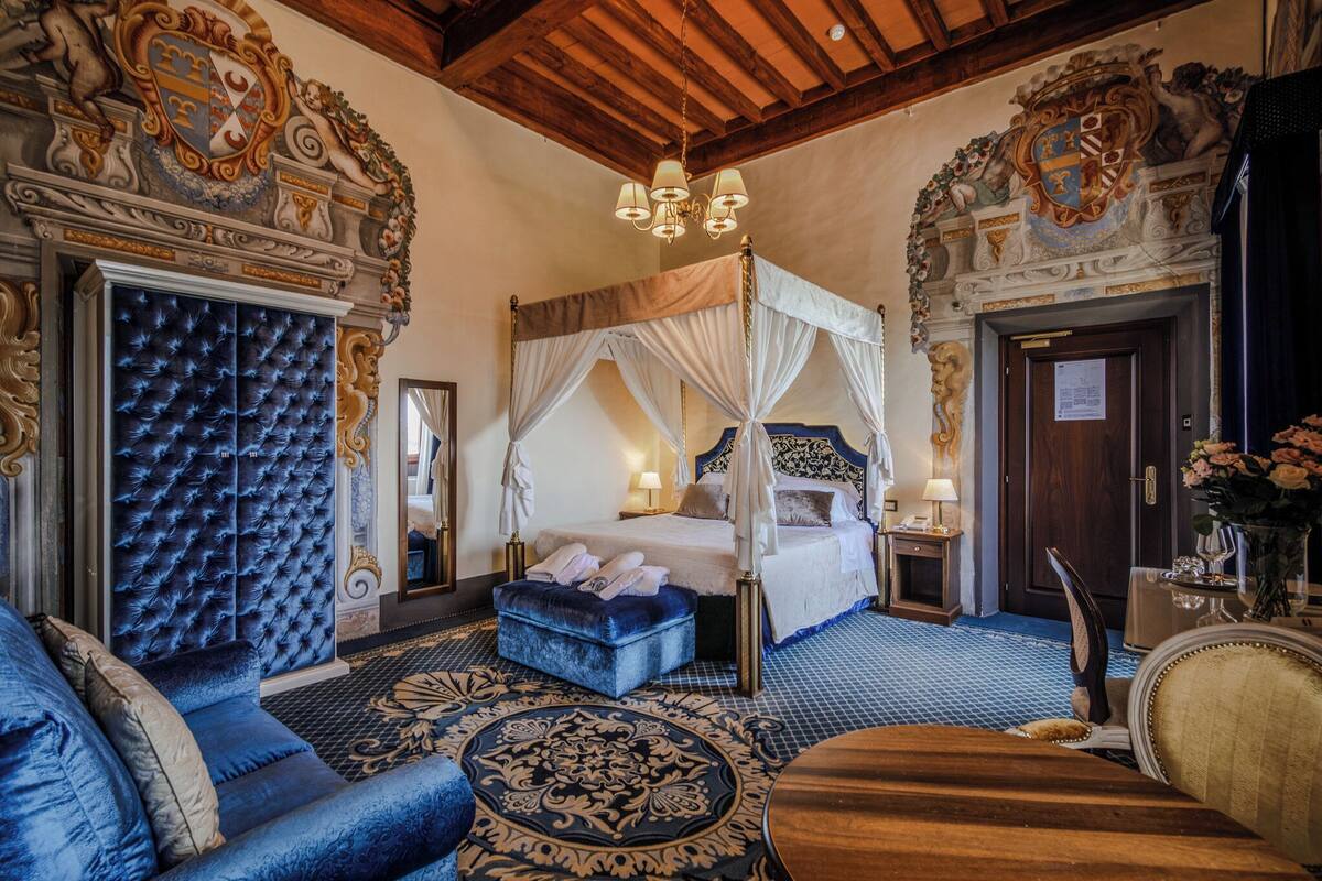A luxurious bedroom with a four-poster bed, a tufted headboard, a canopy bed, and a large mirror.