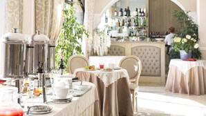 A breakfast setup with coffee machines, a fruit plate, and a bar area with bottles. - Villa Lecchi Hotel Wellness (Poggibonsi)