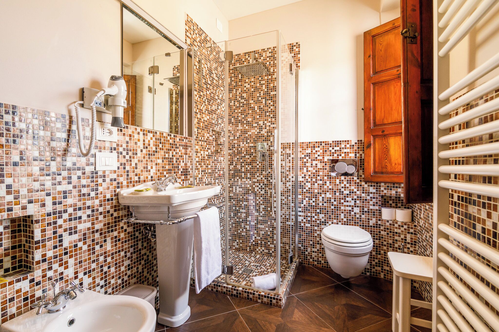A bathroom with a glass-enclosed shower, a sink, a toilet, and a mirror.