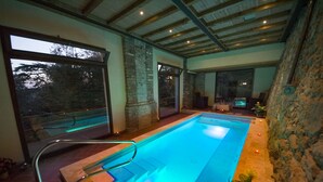 An indoor swimming pool with a glass barrier, stone walls, and large windows. - Villa Lecchi Hotel Wellness (Poggibonsi)
