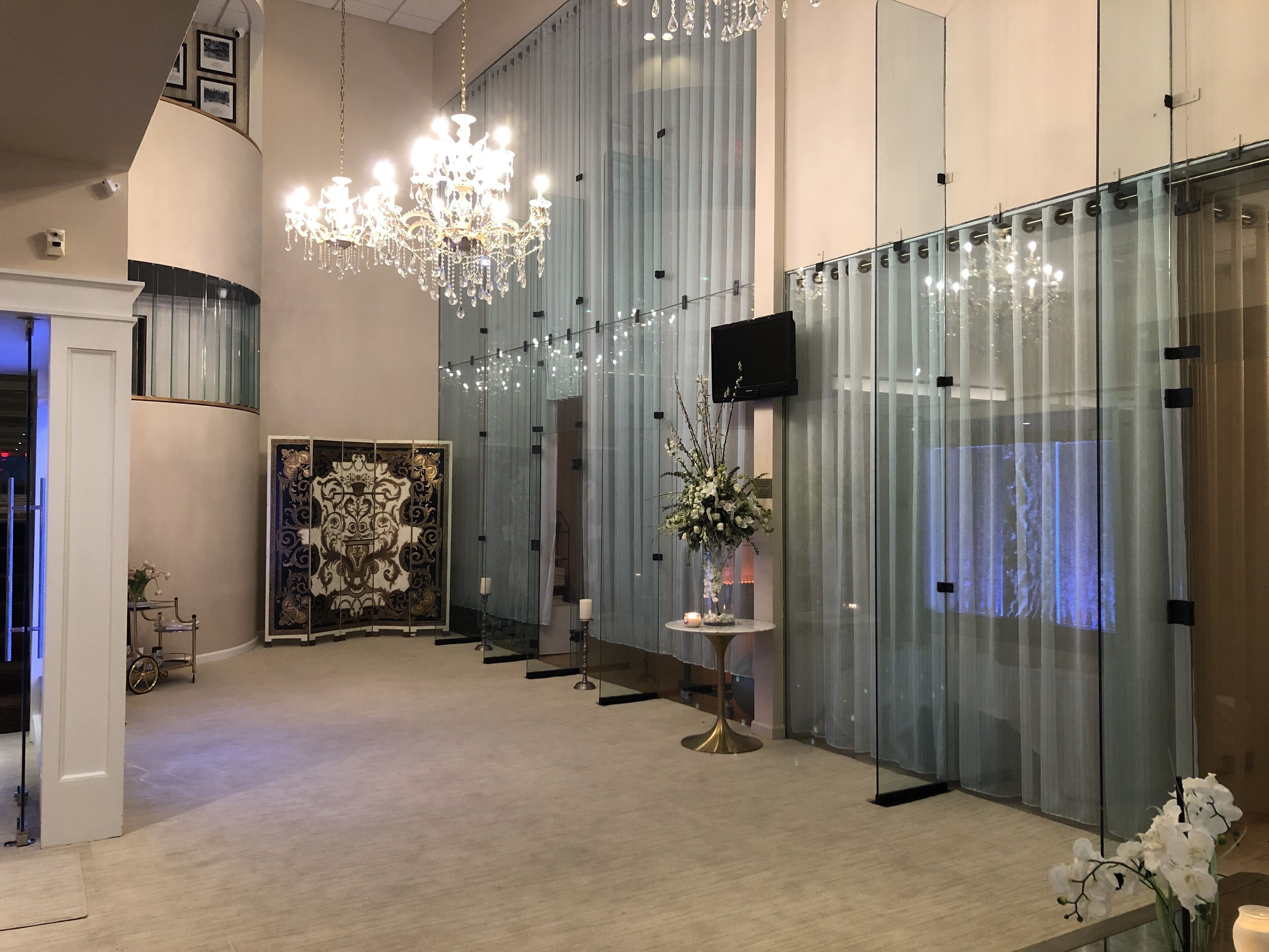 Ein modernes Interieur mit einer Kristallleuchtre, einer großen Dekoration und einer Glastrennwand mit Vorhängen.