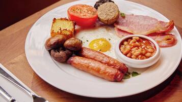 A plate of breakfast food including sausages, eggs, tomatoes, beans, and bacon.