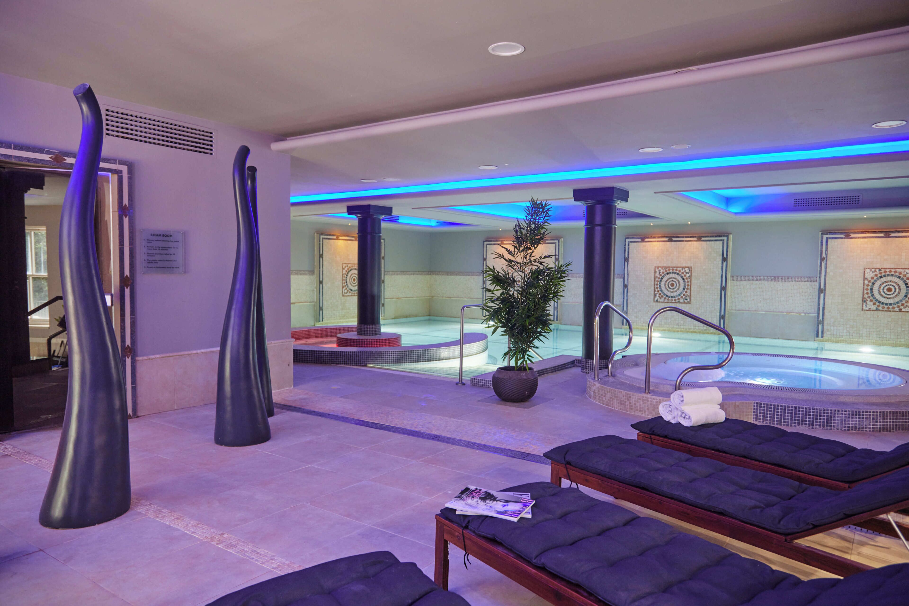 Un espacio de spa con un jacuzzi, sillones reclinables y jarrones decorativos.