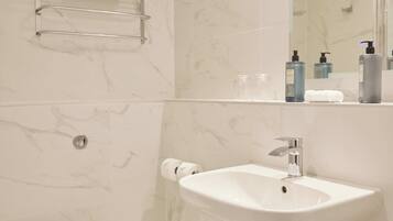Un baño con inodoro, lavamanos, azulejos de mármol y un perchero para toallas.