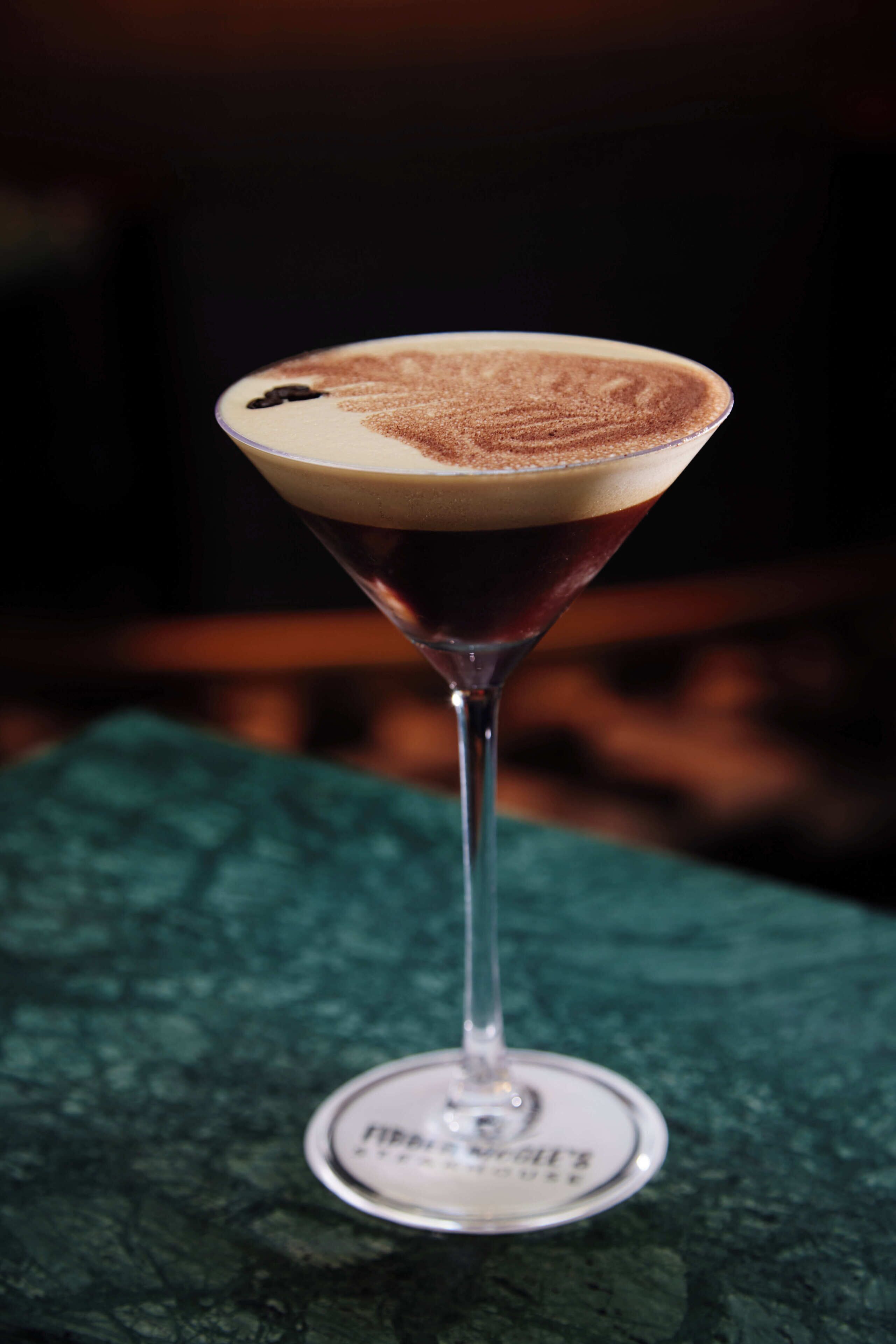 Un verre à martini avec une mousse onctueuse sur une surface texturée.