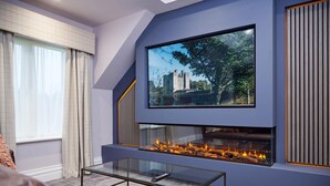 Een moderne woonkamer met een open haard, een groot flatscreen televisietoestel aan de muur en een comfortabele zithoek.