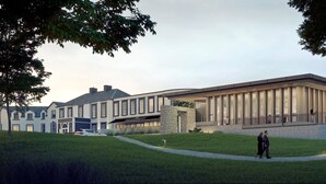 Een modern hotel met een ruime entree, een overdekte doorgang en een aangelegde tuin.